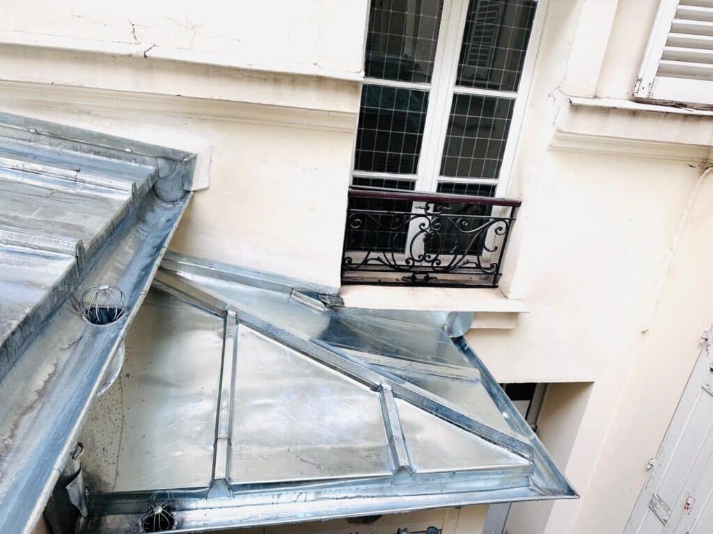 Toiture en verre, façade et balcon parisiens.